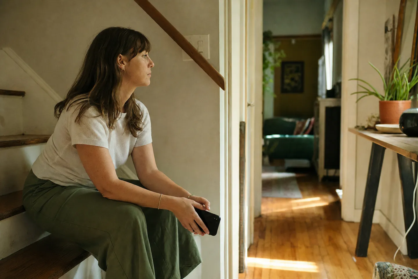 Woman sitting on indoor steps in a quiet home